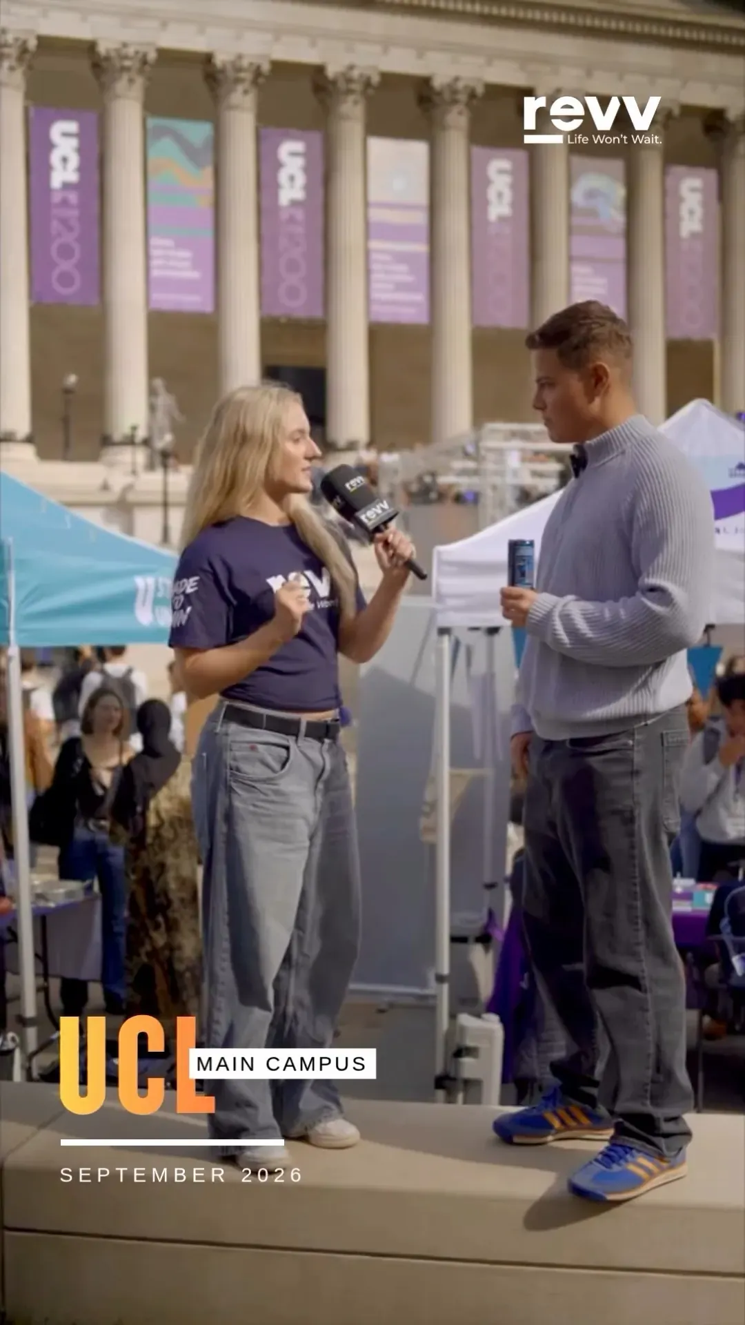 A revv interviewer talking with a student in front of the Wilkins Building colonnade.